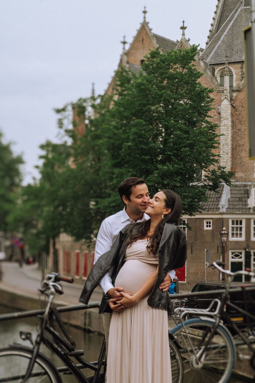 A romantic moment captured in front of historic Dutch architecture with bicycles in the background.