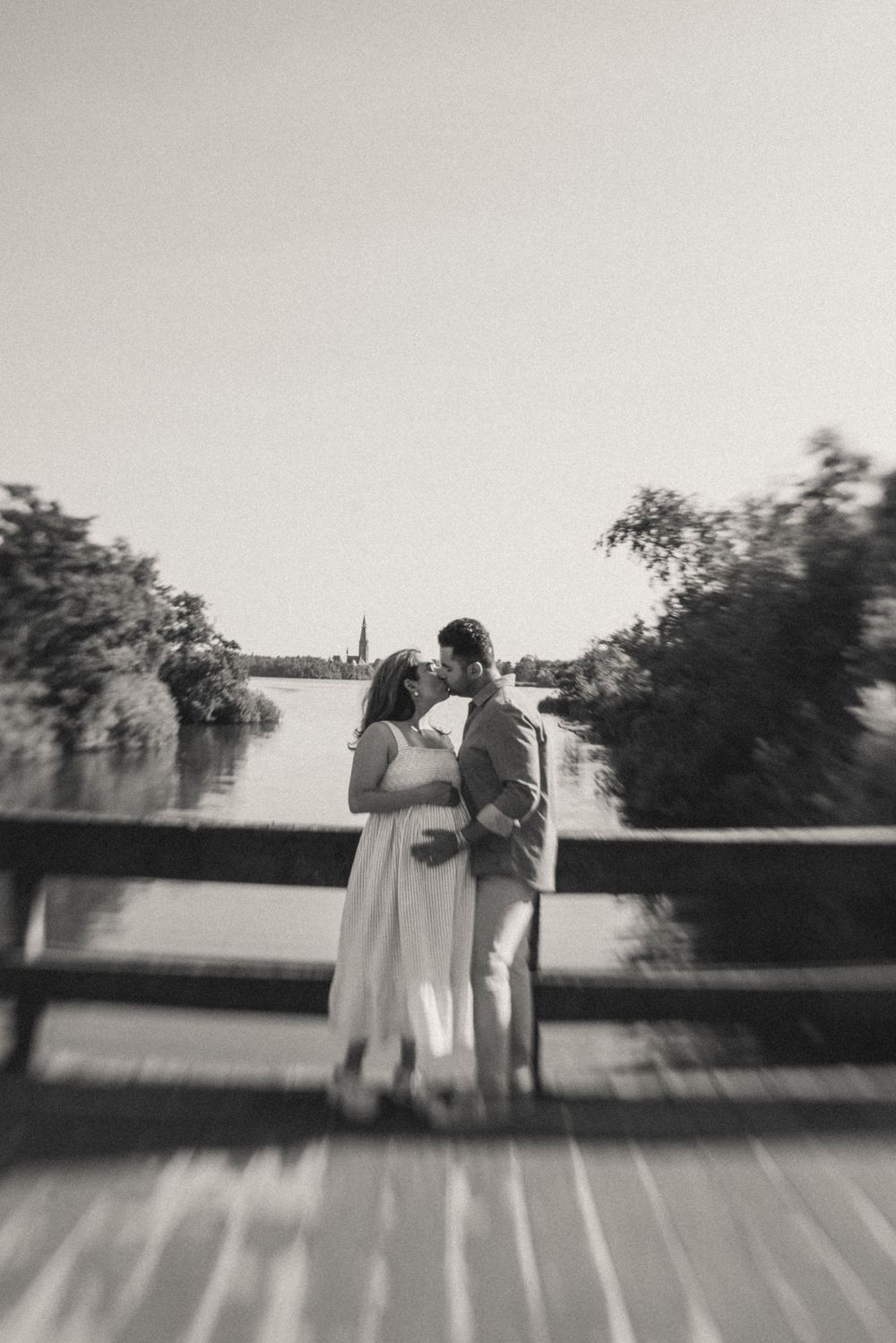 A black and white silhouette of a couple embracing against a bright sky.