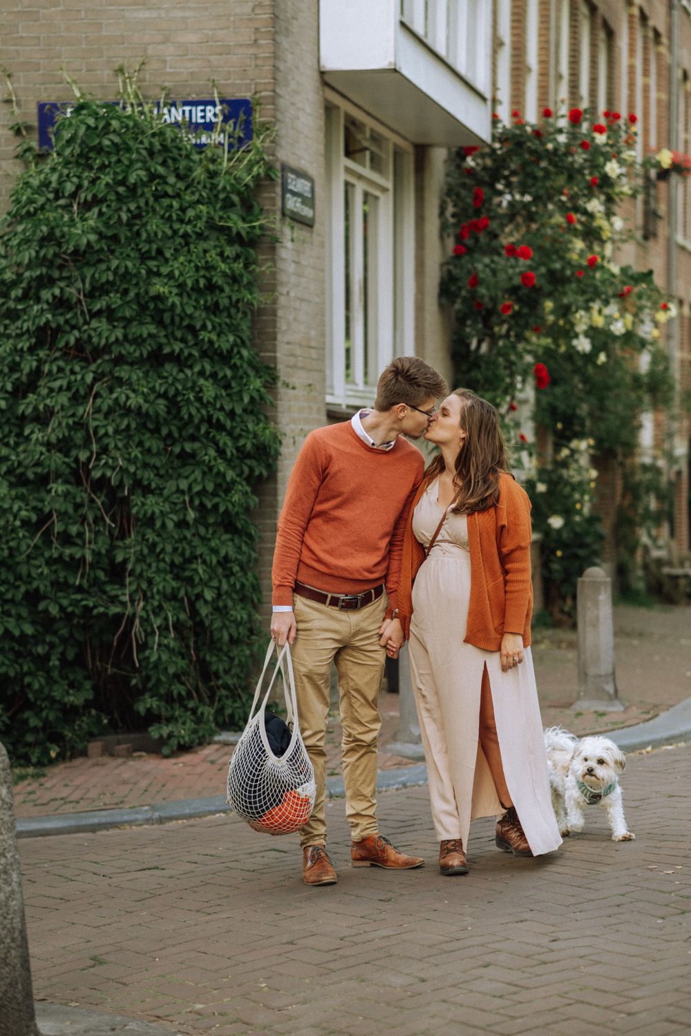 Lifestyle maternity photoshoot with a dog in Amsterdam — couple walking hand in hand