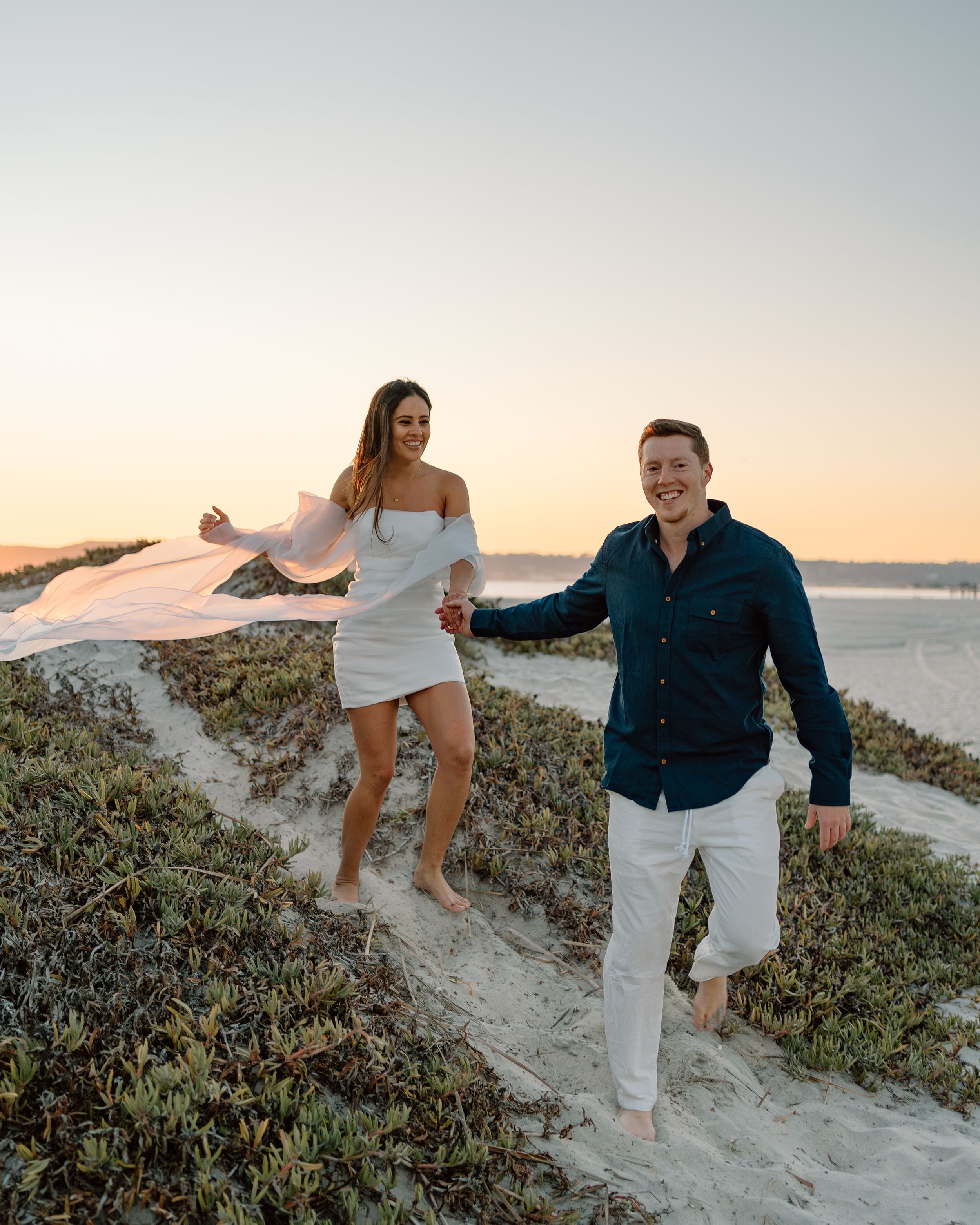 Adventurous beach engagement session in San Diego. Candid couple photography capturing love, laughter, and golden hour magic by the ocean