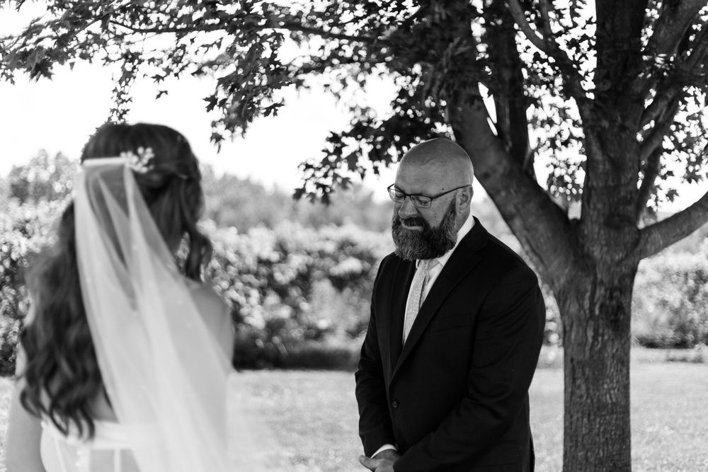 A couple shares an intimate moment together under a tree canopy in a romantic outdoor setting.