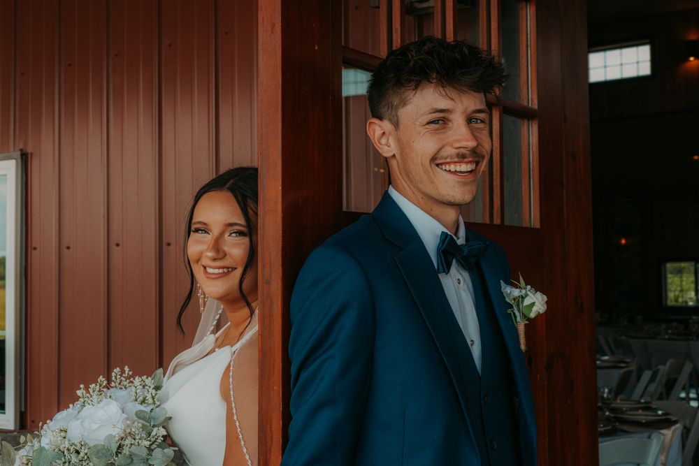 Joyful wedding couple shares intimate moment during rustic barn photoshoot.