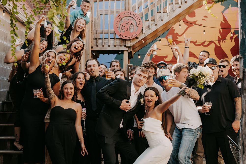 Wedding guests celebrate and dance together during a lively reception party at an indoor venue.