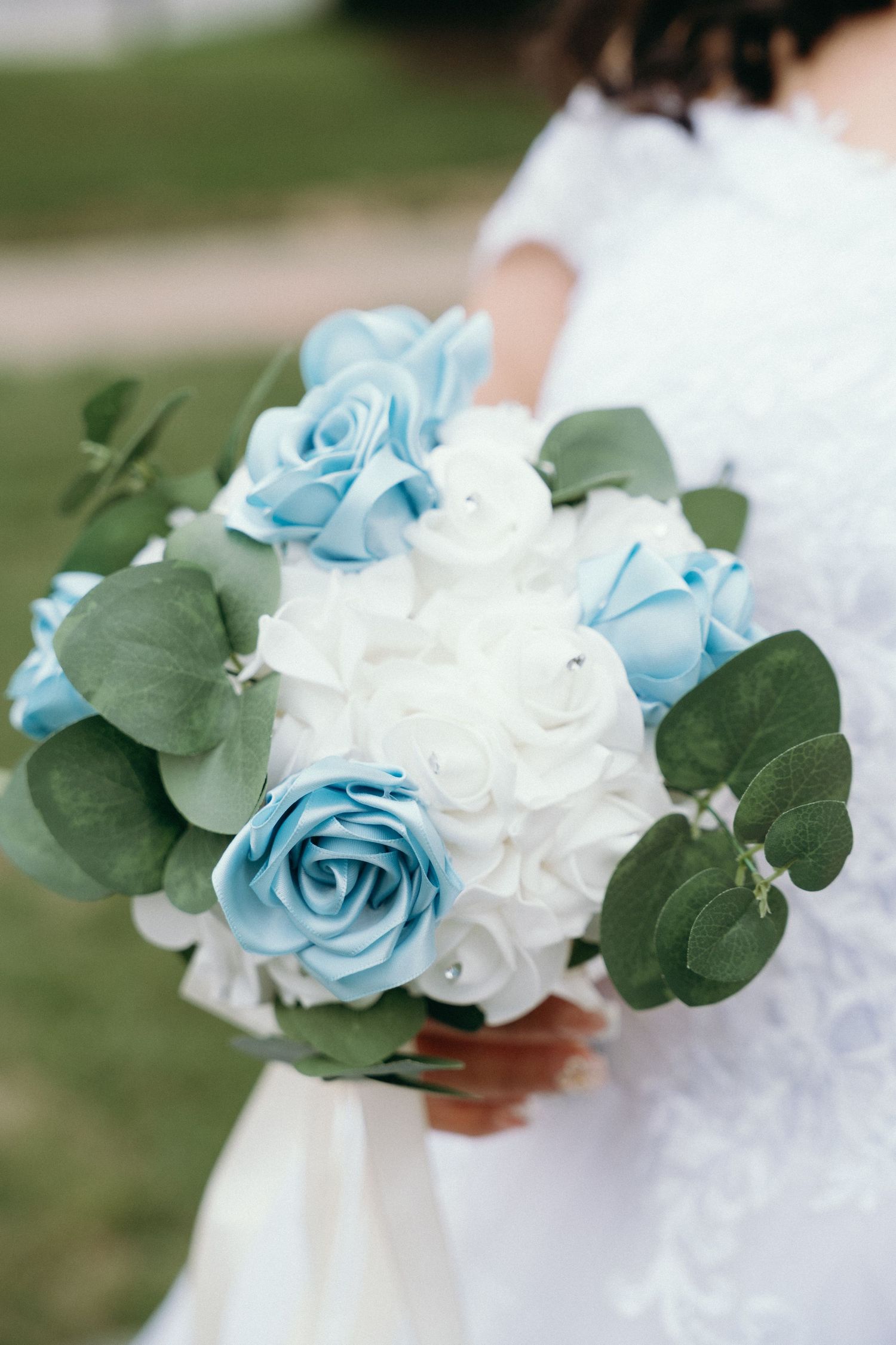 Elegant bridal bouquet featuring blue and white roses with eucalyptus leaves.