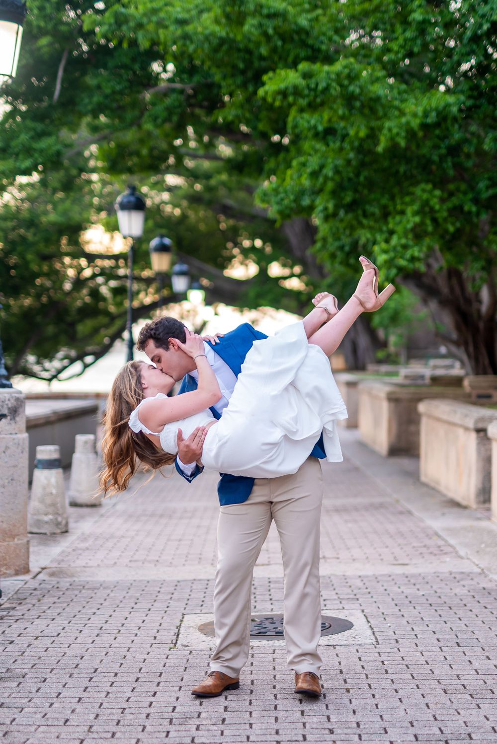 A romantic dip pose on a beautiful tree-lined pathway with vintage lampposts.