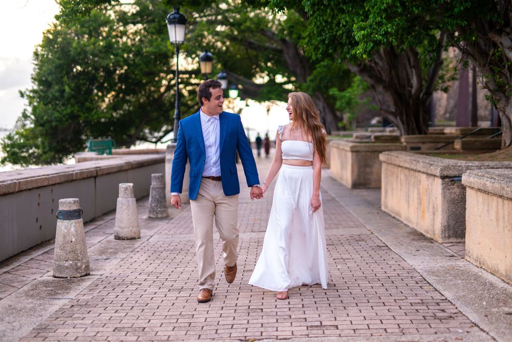 A couple strolls together on a picturesque pathway surrounded by lush greenery.