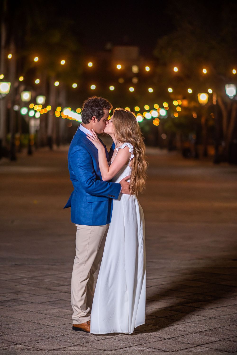 A romantic moment under twinkling lights with a couple in evening wear.