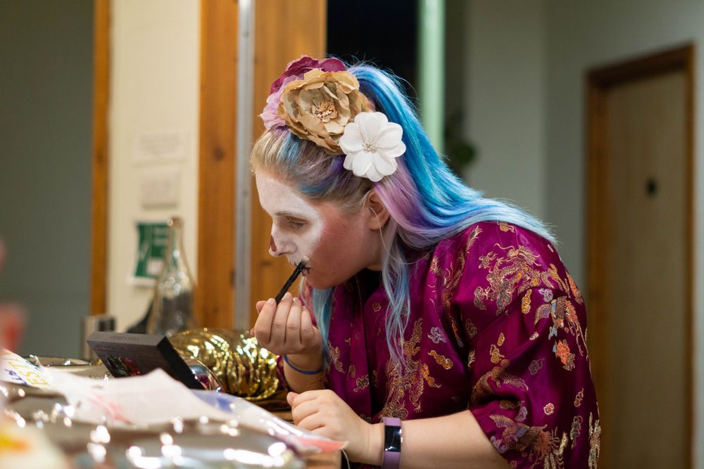 event photography Brighton, back stage photo of a circus performer putting on make up wearing dressing gown and blue hair