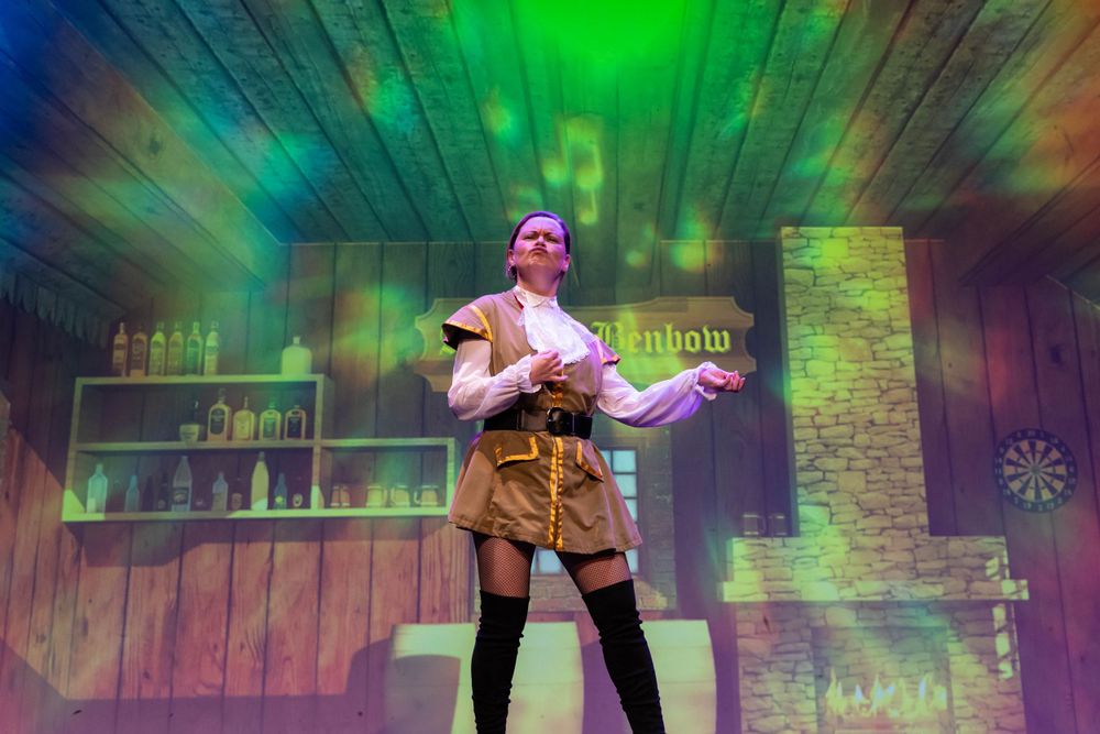 theatre photography Brighton a woman stands. on stage in costume with disco lights in the back ground its a pantomime