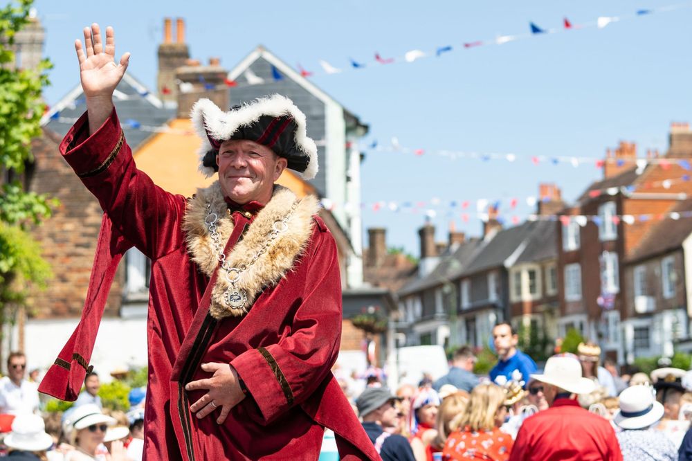 event photography brighten of a local mayor at a street party he waves to the crowd wearing a red velvet mayors coat