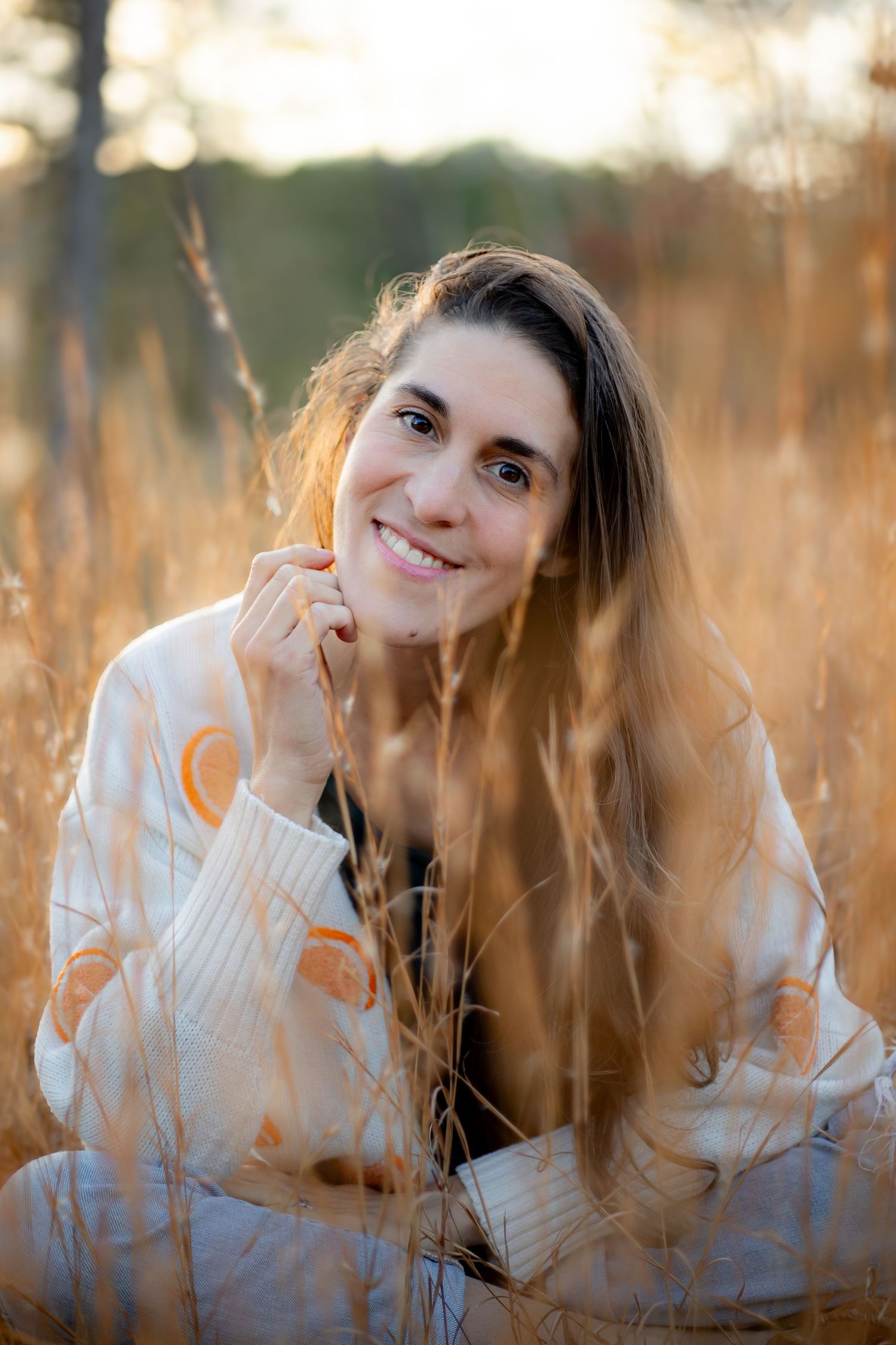 Portrait in tall autumn grass with golden sunlight filtering through trees.