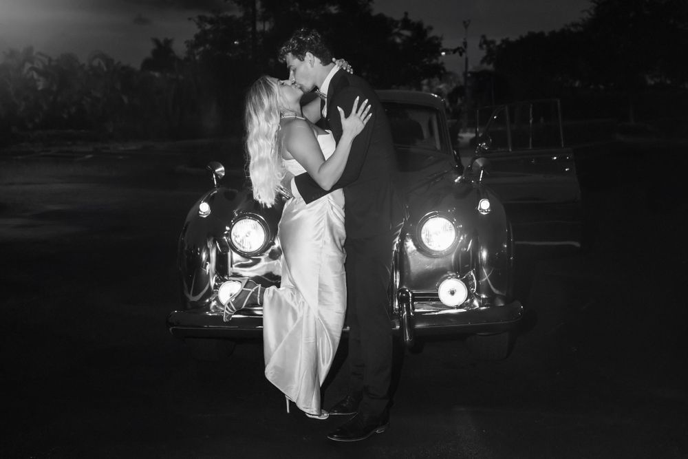Bride and groom embracing with glowing Hard Rock Guitar Hotel in the night sky background, romantic South Florida wedding portrait