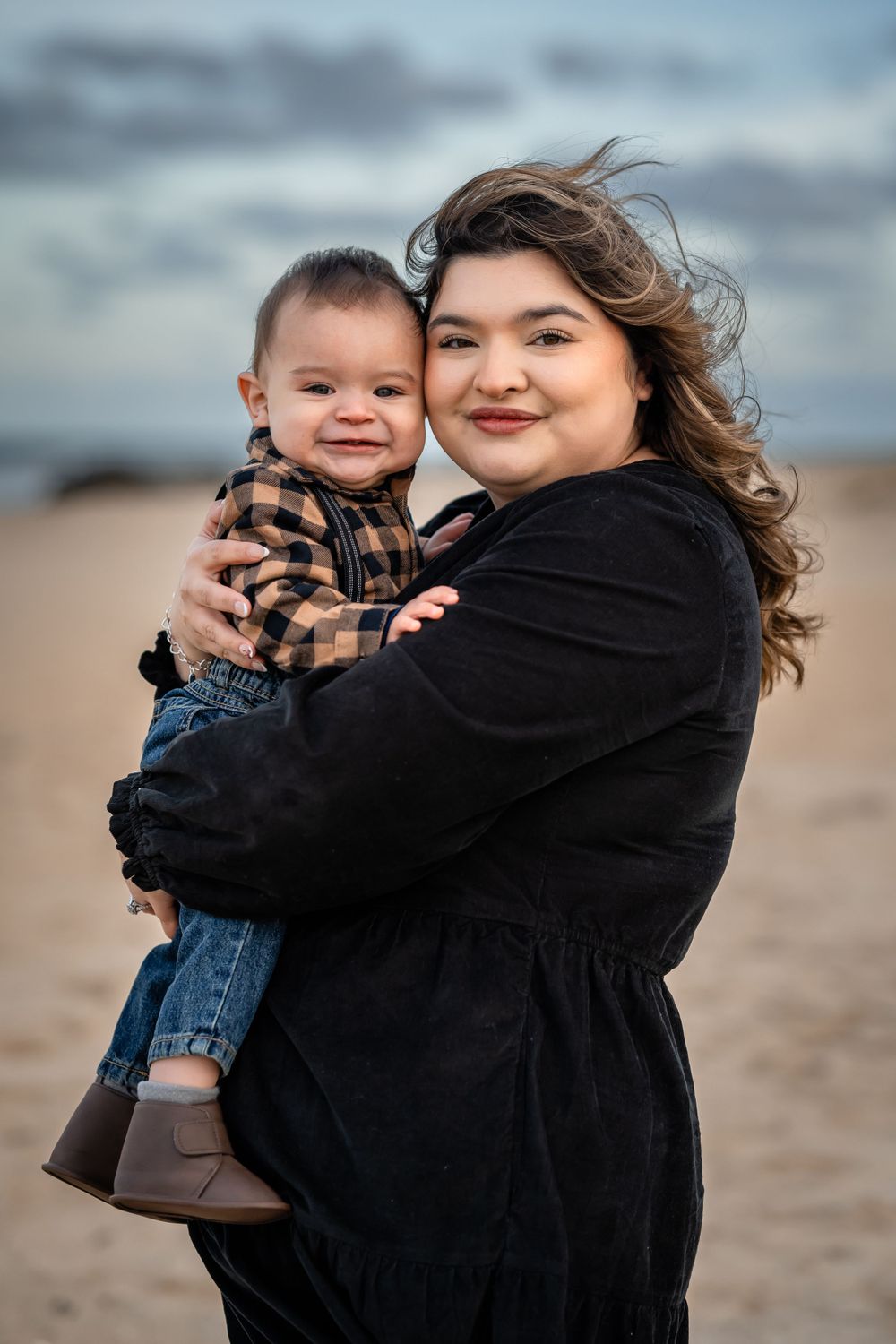 A heartwarming embrace between parent and child on a beach with cloudy sky backdrop.