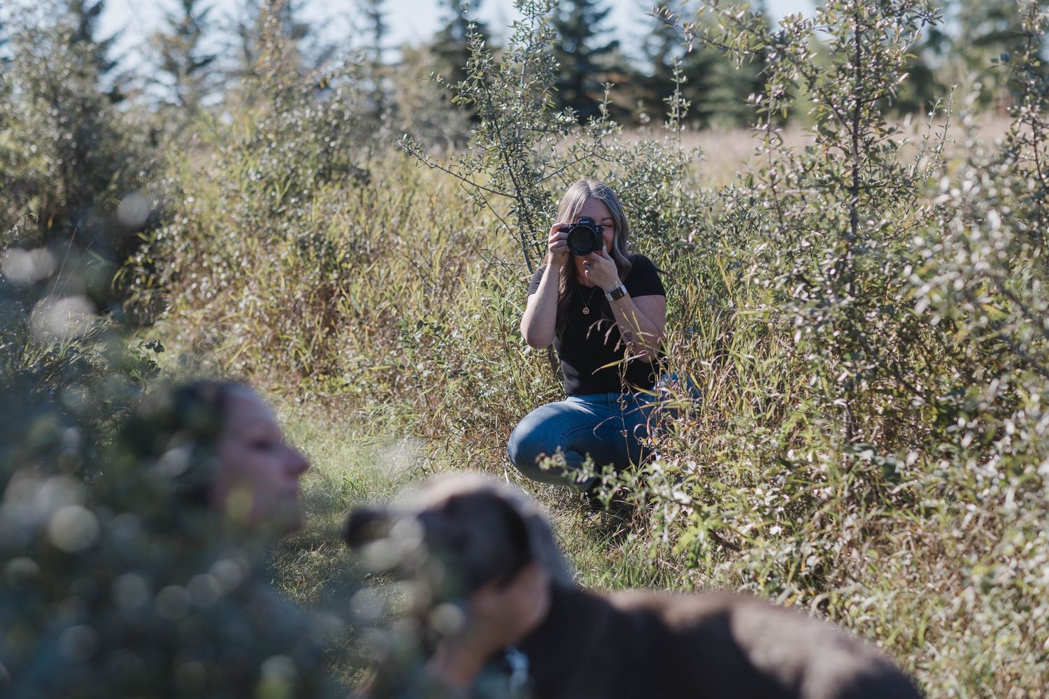 A photographer shooting in a field surrounded by natural foliage.