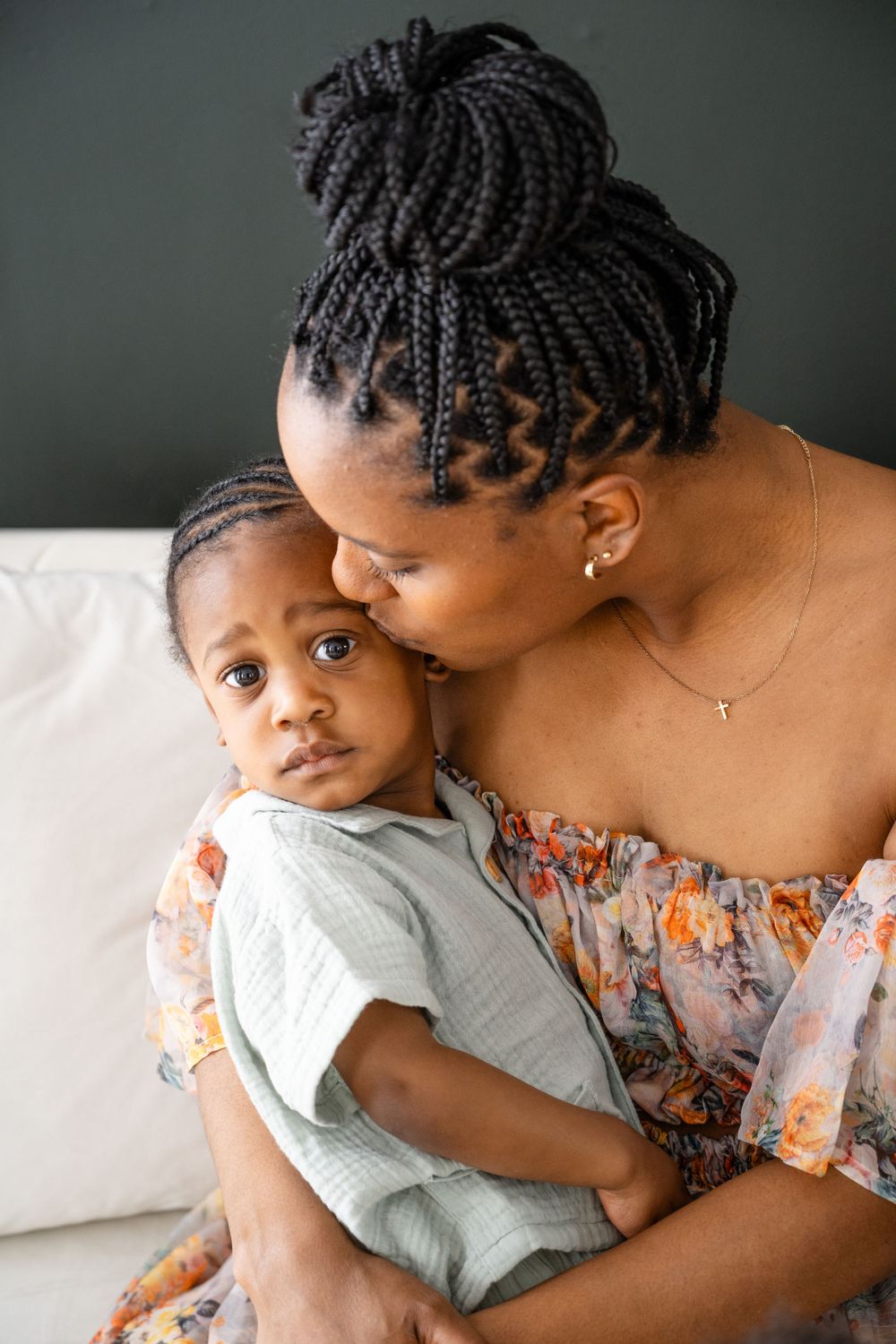 Close-up portrait showing tender moment in soft lighting on white sofa.