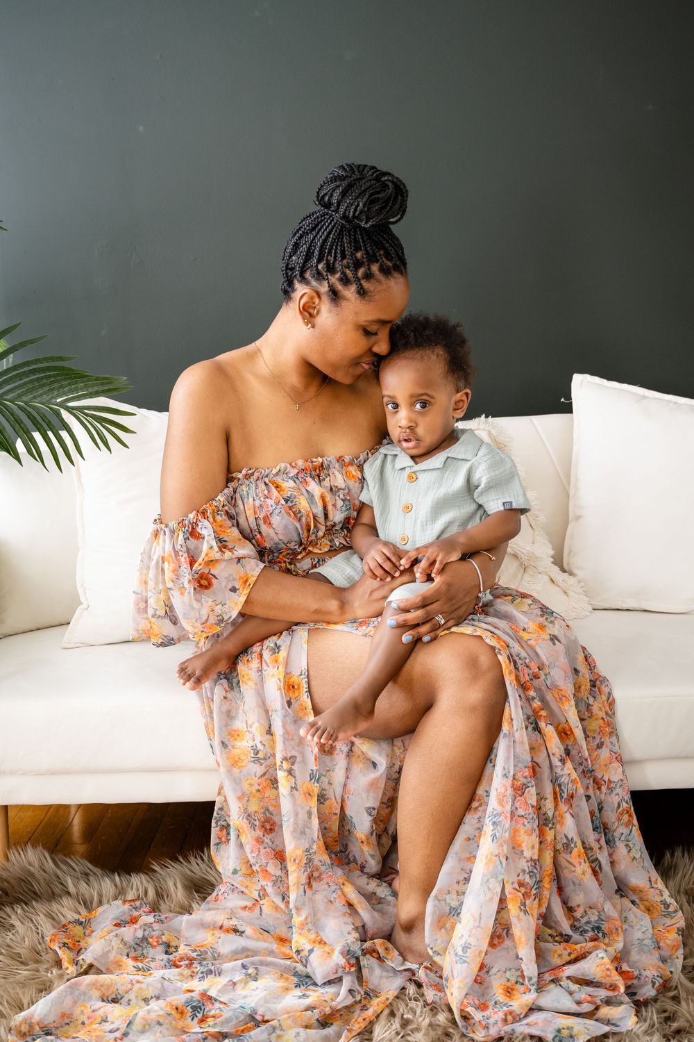 Intimate indoor portrait showing tender connection on white sofa with floral dress.