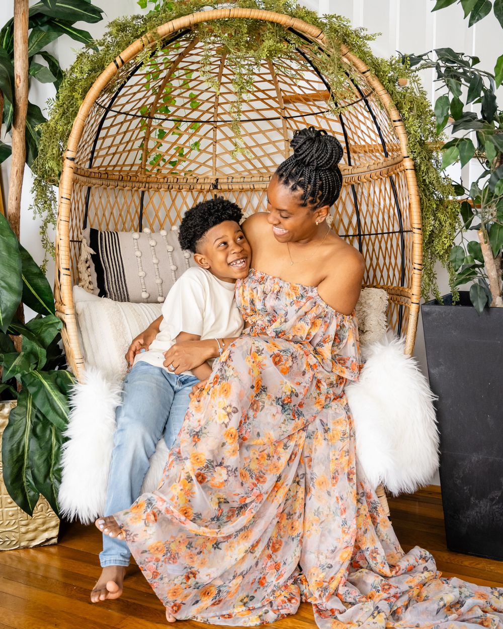 Joyful moment captured in decorative rattan chair with floral dress and greenery.