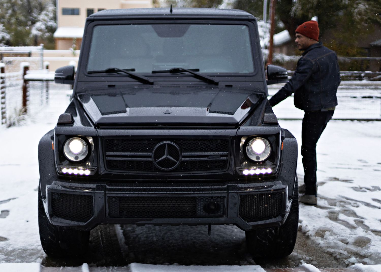 Black Mercedes G-Wagon parked in snowy driveway.