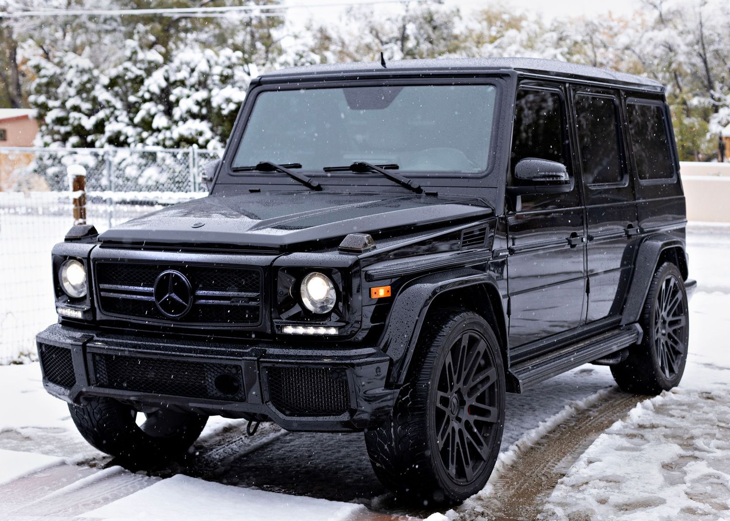 Black Mercedes G-Wagon SUV parked in snowy conditions with black wheels and aggressive styling.