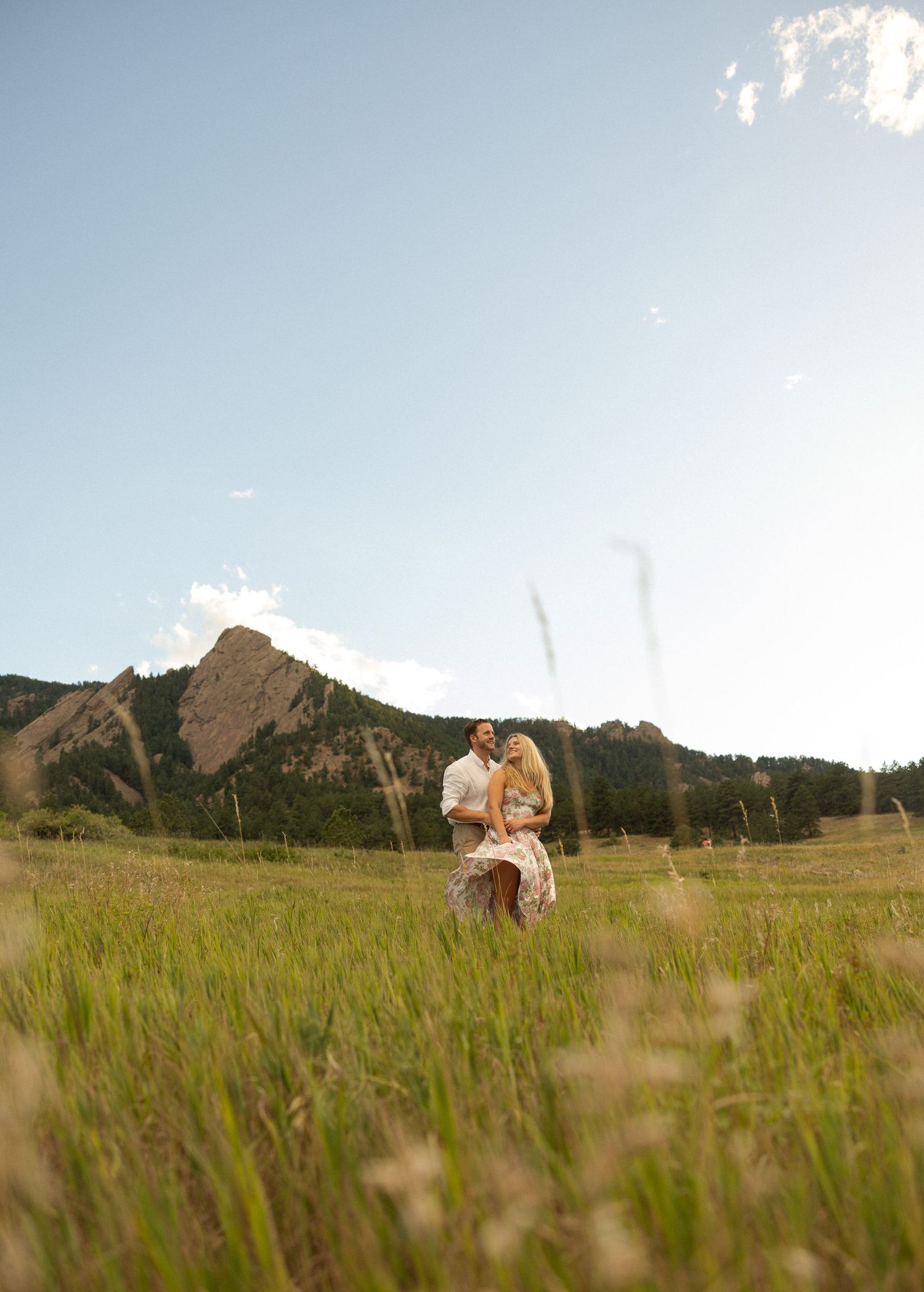 A couple shares an intimate moment in a mountain meadow with tall grass.