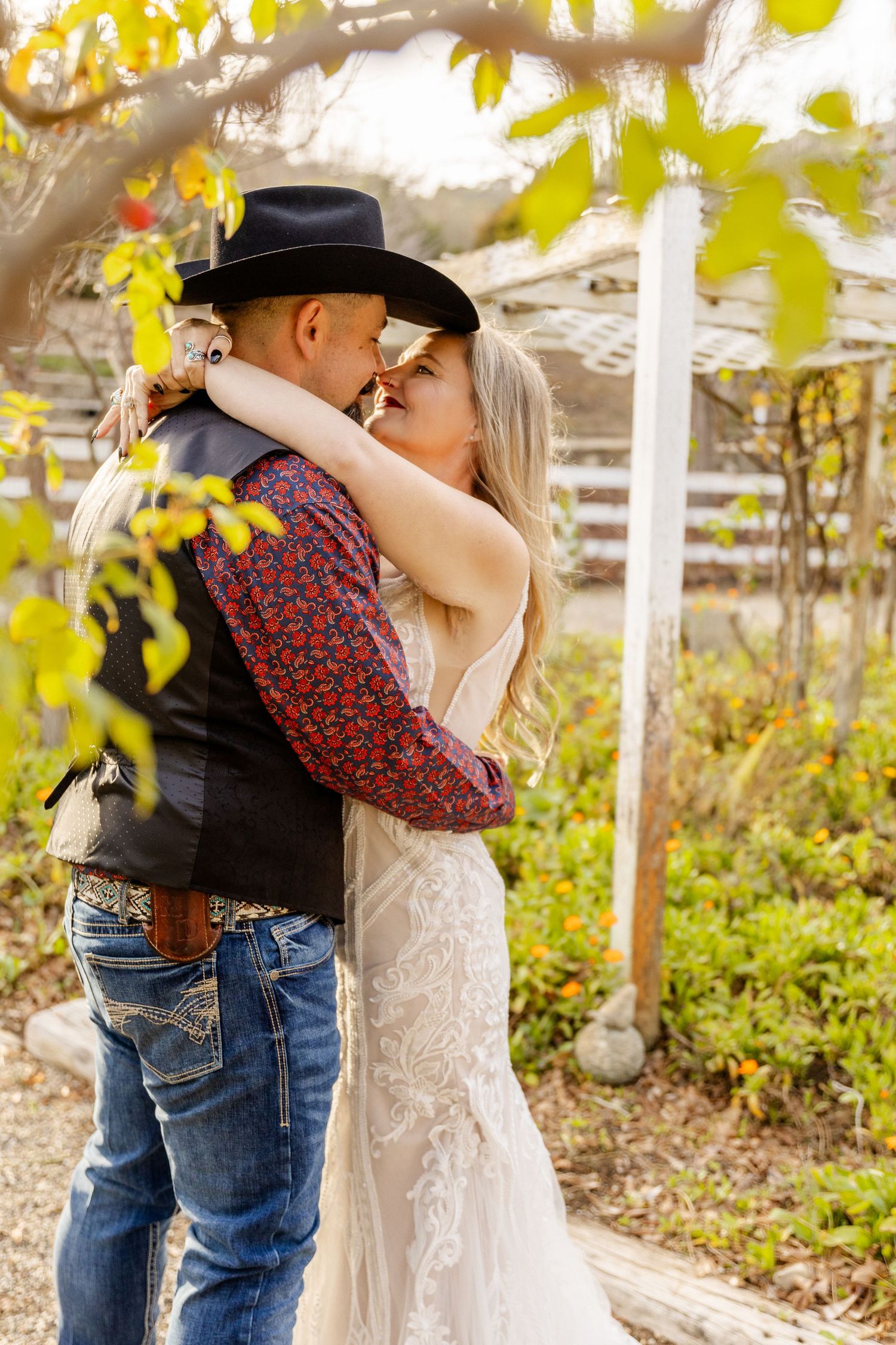 A romantic moment captured between a couple in western attire among autumn leaves.