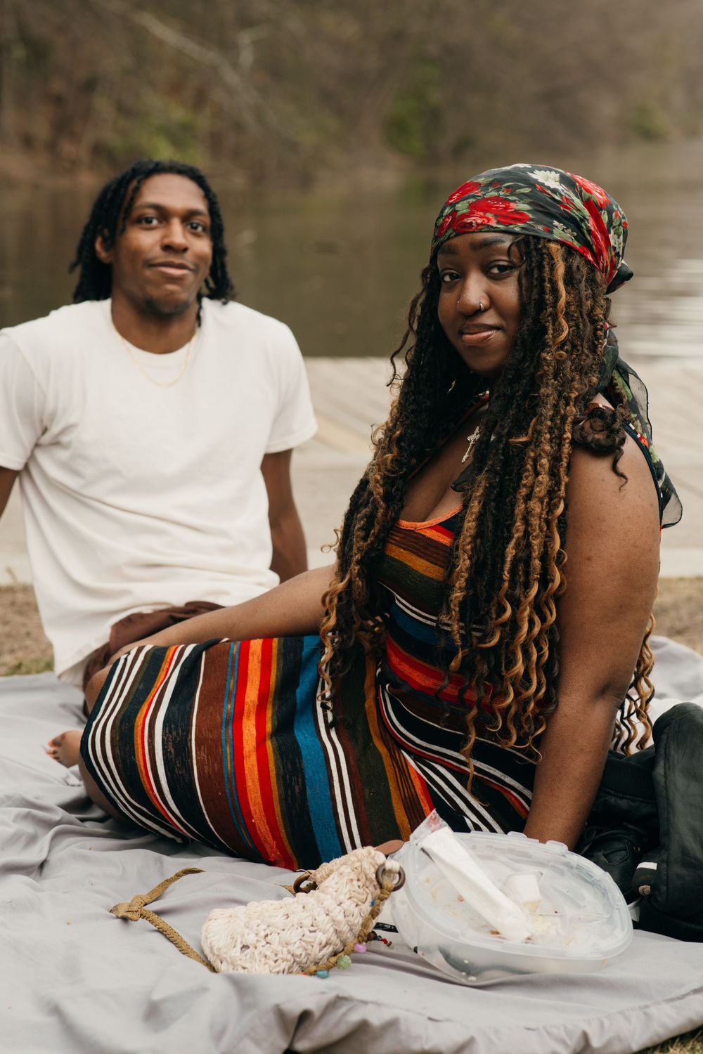 A couple enjoys a romantic picnic outdoors with colorful striped attire and long dreadlocks at Piedmont park in Atlanta, Ga.