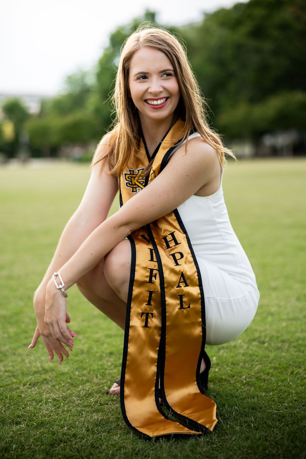 Kennesaw State University Graduate 2025 squatting while wearing her graduation sash.