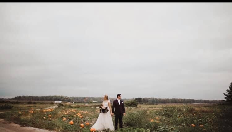 Minimalist wedding portrait of couple standing in rustic countryside landscape.