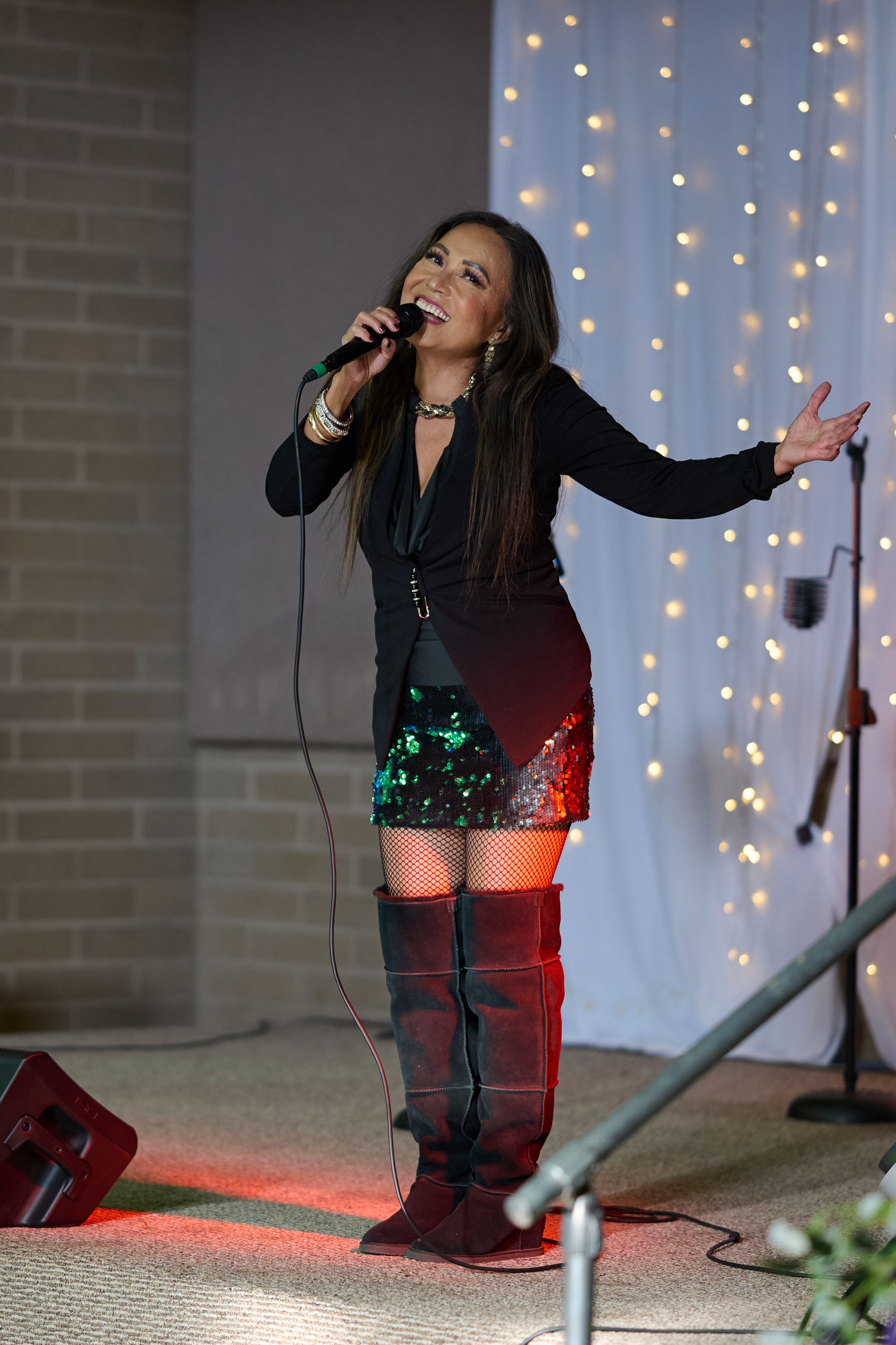 A performer in a black top and sparkly shorts sings passionately on stage at St. Michael's Catholic Church Stockton California.