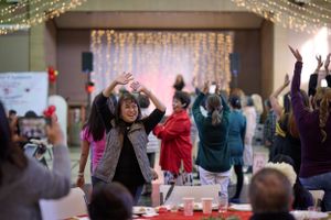 Joyful people dance with their arms raised during a festive indoor celebration at St. Michael's Catholic Church Stockton California.