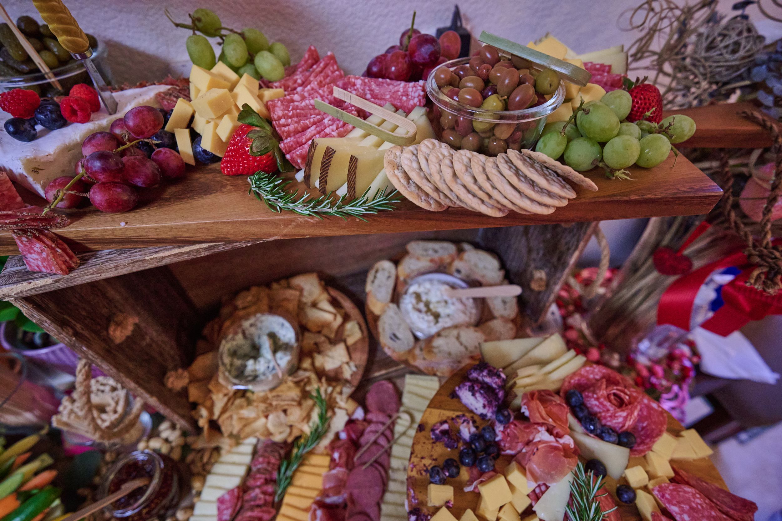 Elegant charcuterie board featuring meats, cheeses, fruits, nuts and crackers arranged on wooden serving platters.