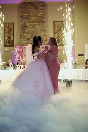 A couple shares their first dance on a misty dance floor with dramatic sparkler fountains illuminating the romantic moment.