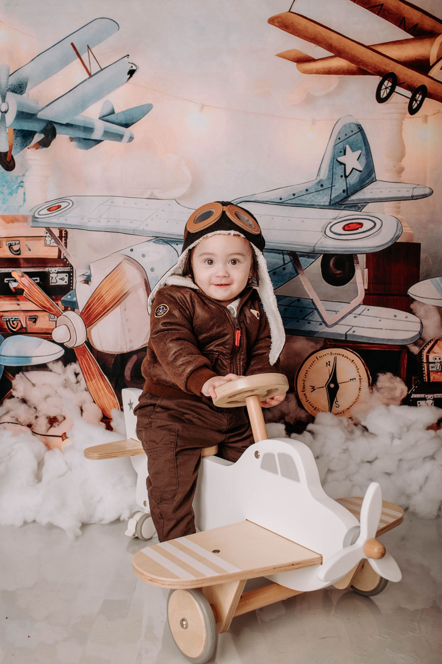 Vintage aviation themed setup with wooden ride-on plane and retro suitcase decorations.
