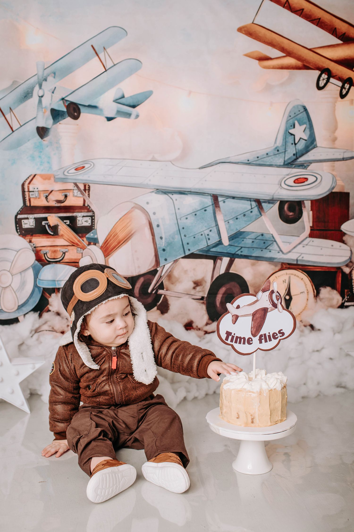 Aviation themed cake smash setup with vintage decorations and white frosted cake.