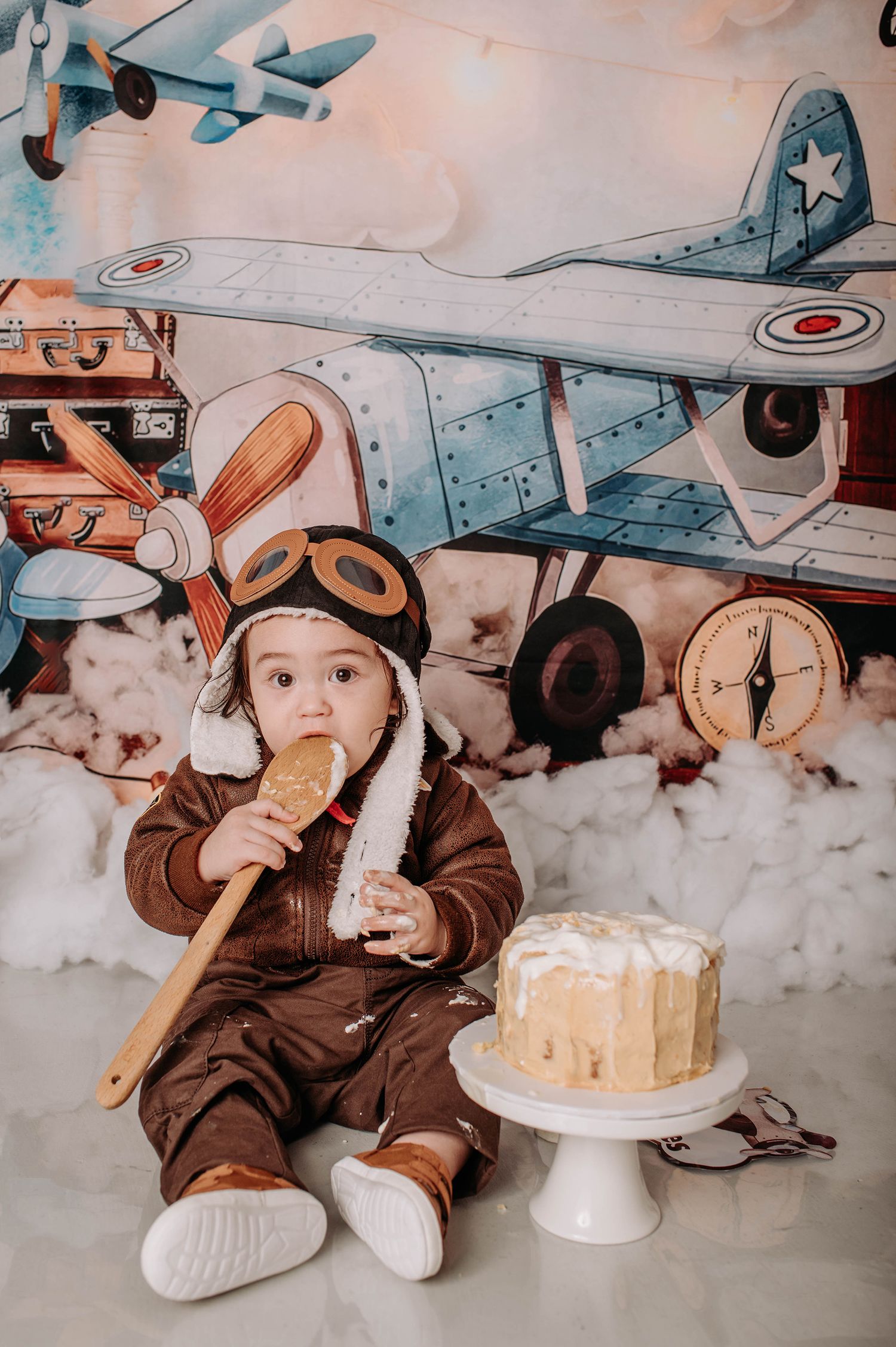 Vintage aviation scene with white cake on pedestal and decorative planes in background.