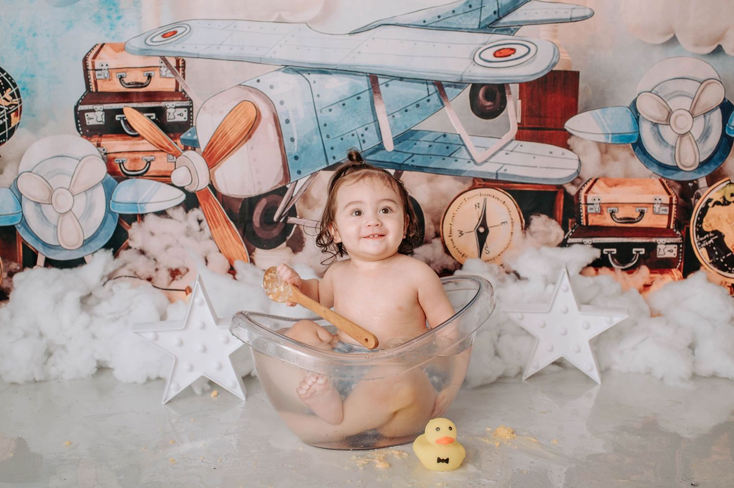 Bath themed photo setup with clear bowl, rubber duck, and vintage aviation decorations.