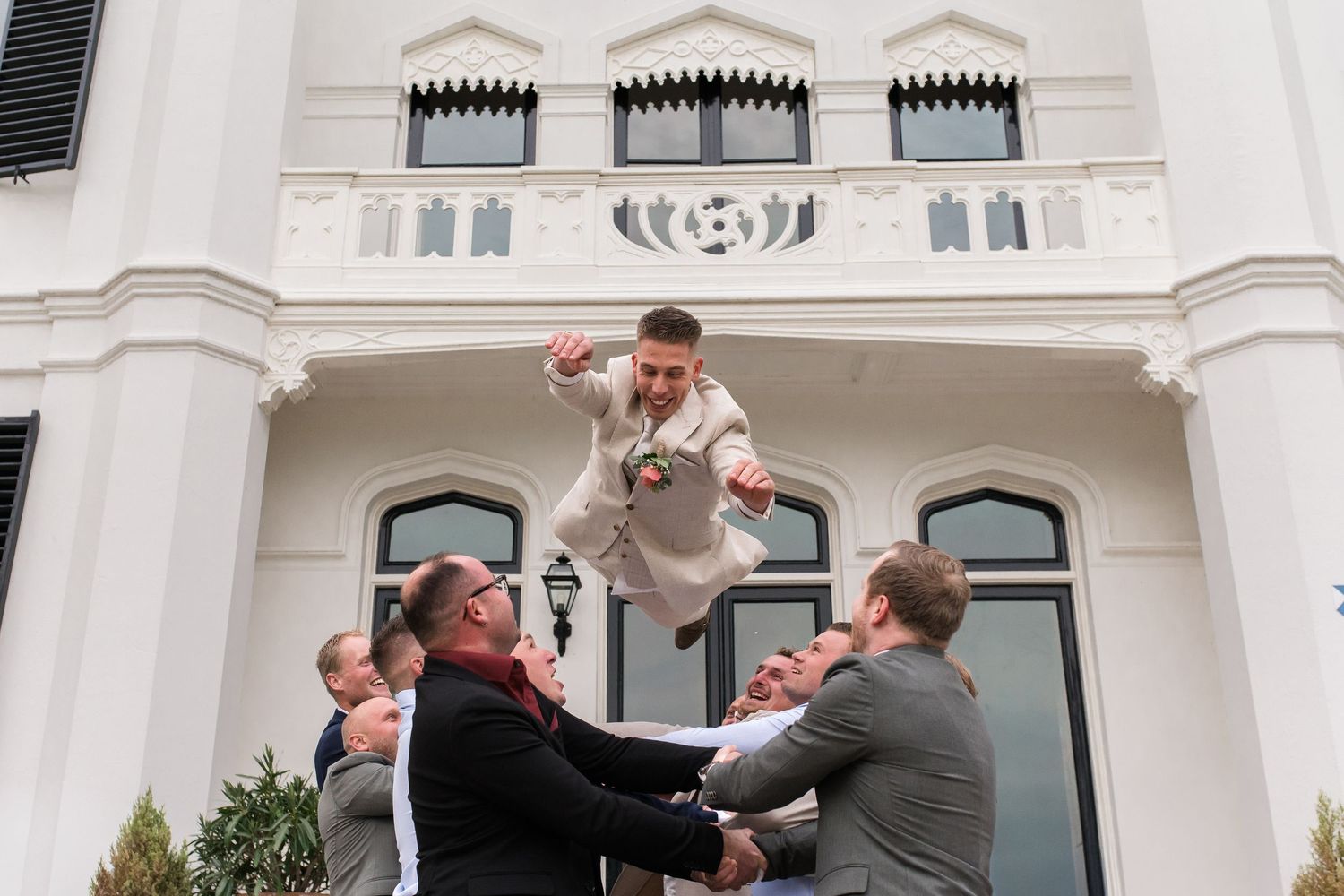Bruidegom vliegt tijdens de groepsfoto's van de fotoshoot op oranjerie sandenburg