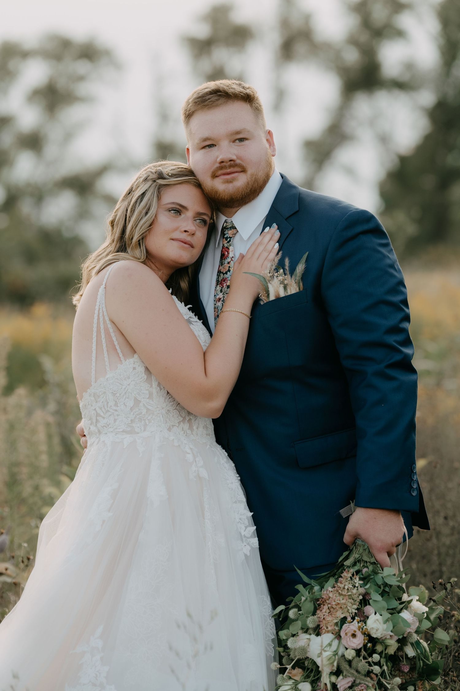 A romantic wedding couple embraces in a wildflower field during their outdoor photoshoot.