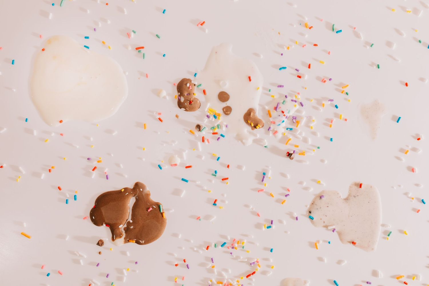 An Image of melted ice cream spots and sprinkles on a white backdrop.