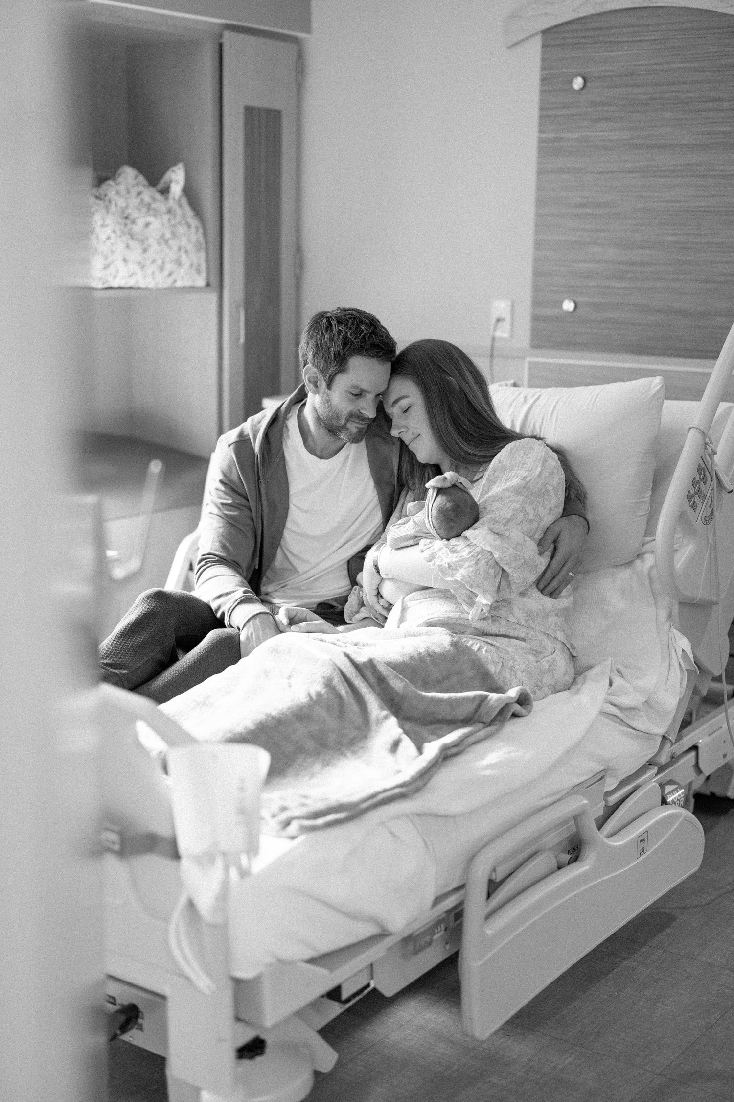A black and white photo showing a new mom and dad in a hospital room with their newborn baby during a Fresh 48 session in Pittsburgh, PA.