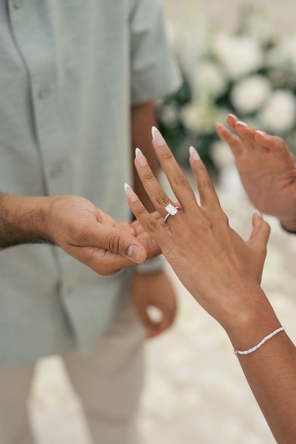 A sequence of hands showing a wedding ring being placed on a finger during a marriage ceremony.