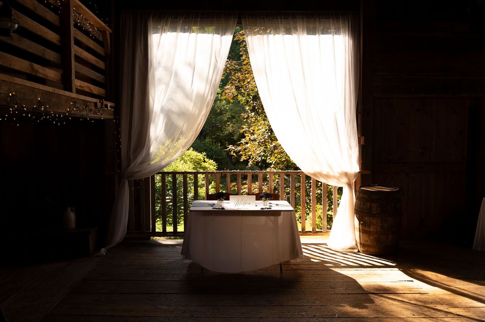Sunlight streams through sheer white curtains in a rustic wedding venue.