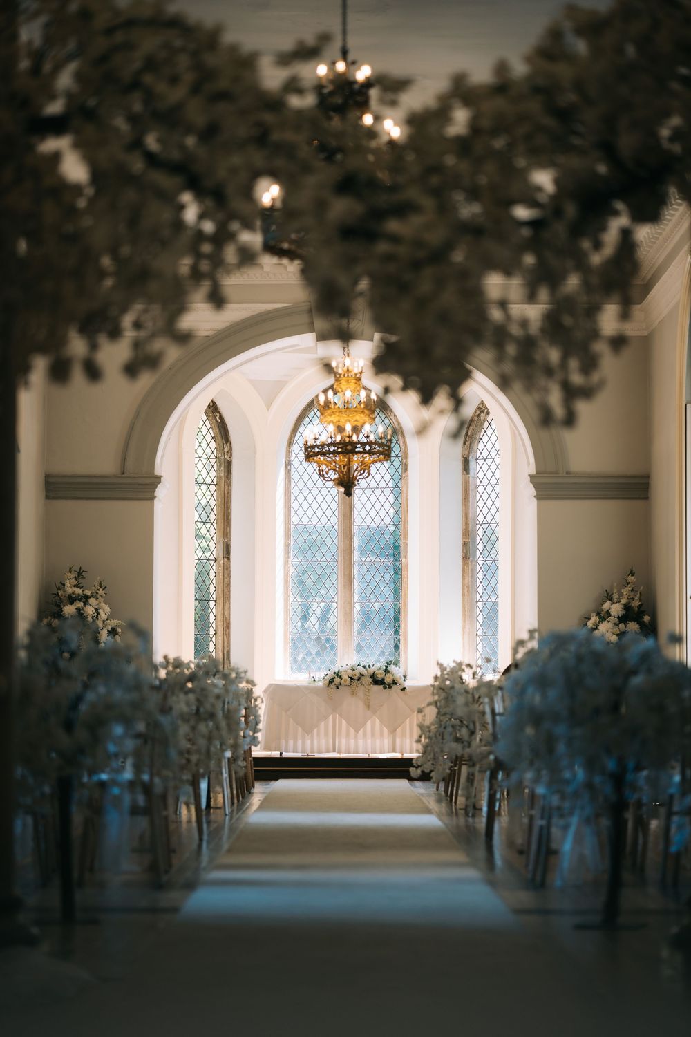 Elegant chapel interior with arched windows and floral decorations lining the aisle.