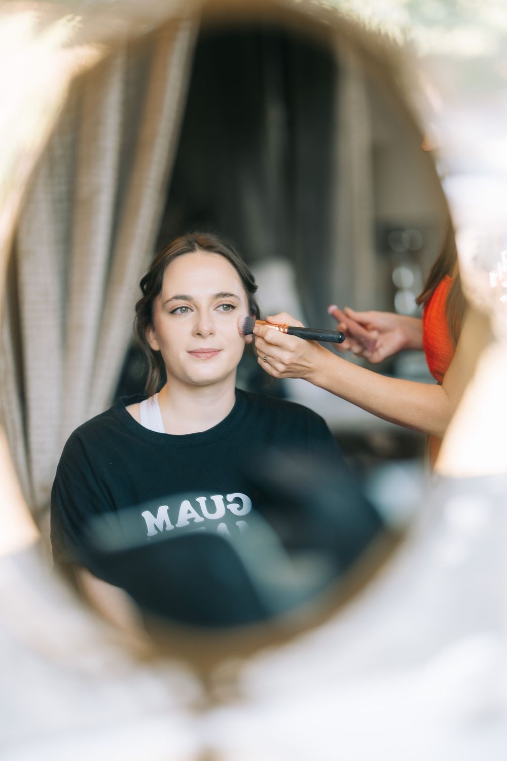 A series of circular mirror reflections showing someone getting makeup applied.