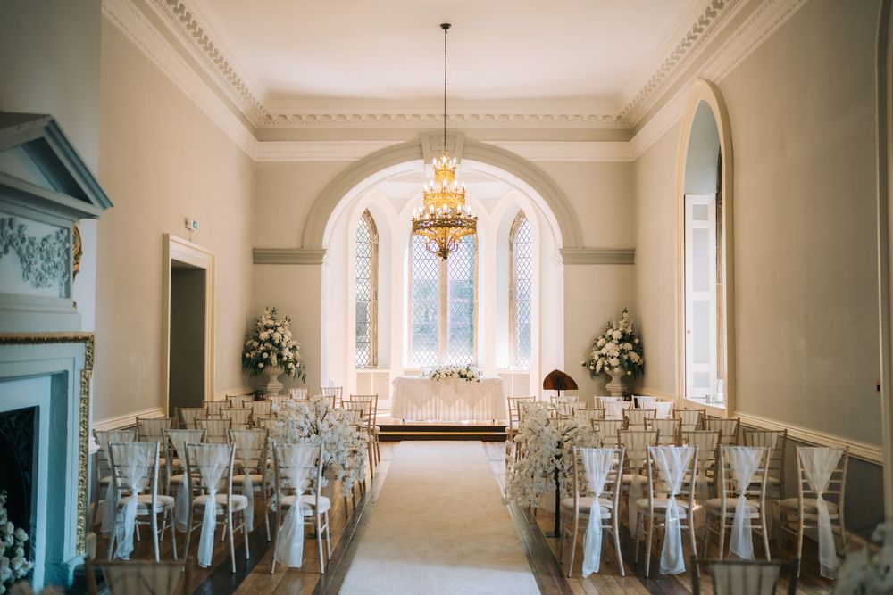 Grand reception hall with chandelier and arched windows in classic white decor.