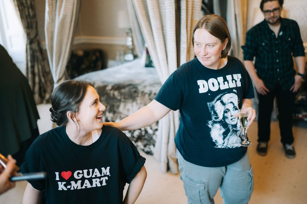 Two people sharing a joyful moment in casual t-shirts with text prints while someone watches in the background.