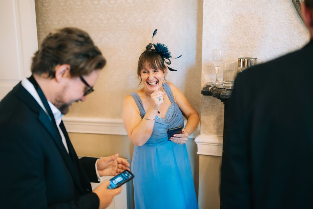 Candid moment of people in formal attire sharing a joyful interaction at an indoor event.
