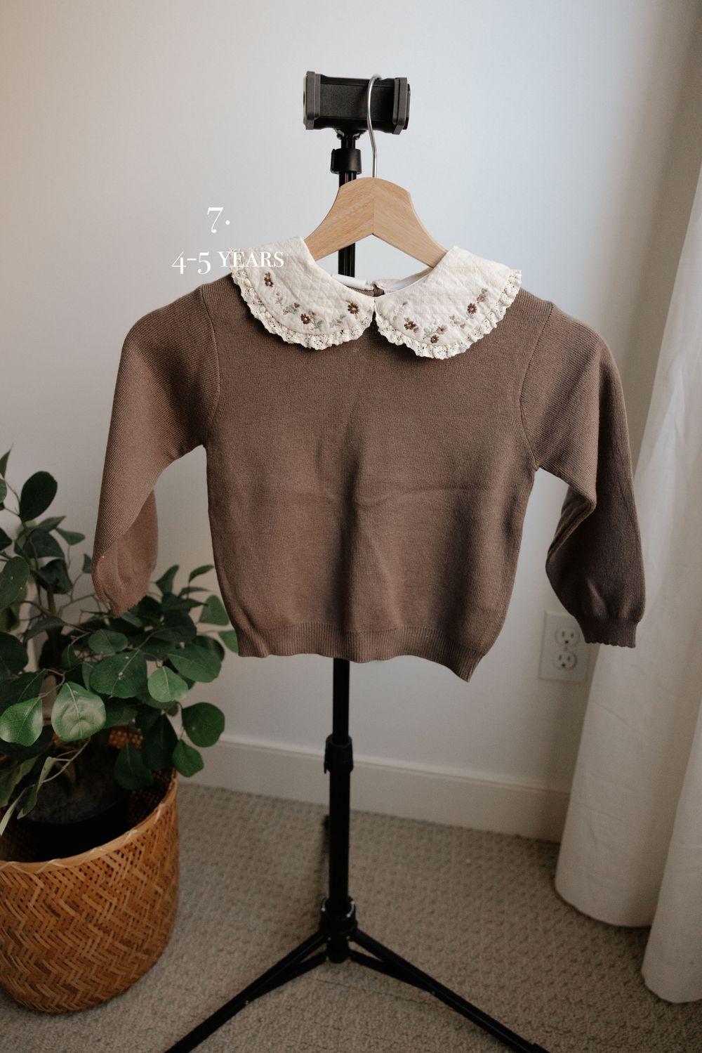 Brown sweater with white lace peter pan collar displayed on photography stand.
