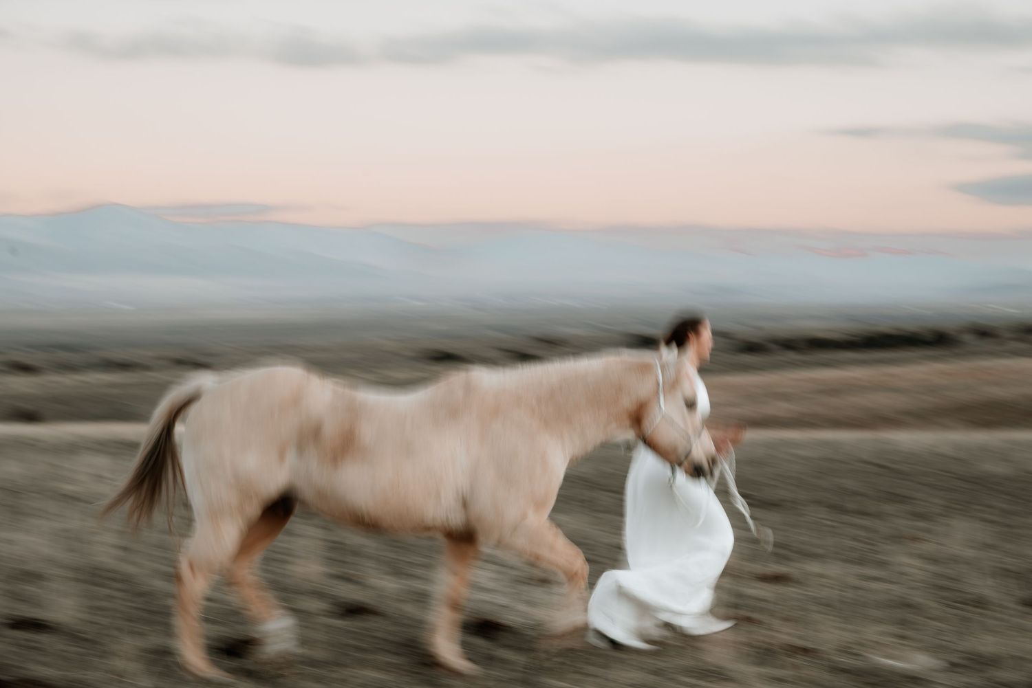 Artistic bridal styled image of bride running with a horse.