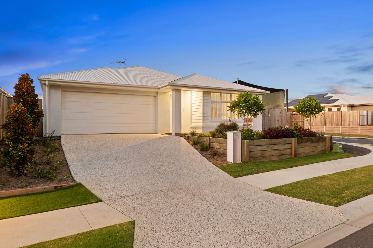 Landscaped driveway with cypress trees leading to a modern residential property.